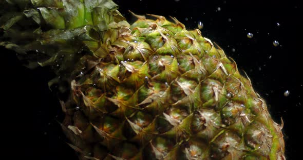 A Whole Pineapple Falls Under Water with Air Bubbles. 