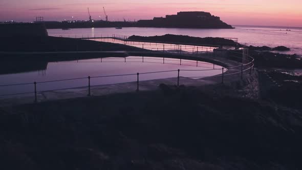 Guernsey tidal bathing pools and Cornet Castle at sunrise, Channel Islands, UK. Aerial drone view