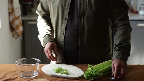 vegetarian man cuts Celery on a chalkboard in the kitchen with a knife
