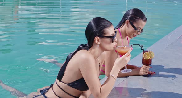 Adorable Women Drinking Cocktails While Swimming in Pool