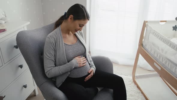 Woman in advanced pregnancy sitting in the armchair and stroking her abdomen. Shot with RED helium c