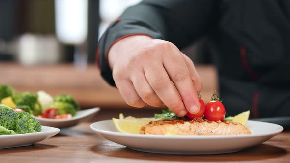 Cook Man Finishing Meal Fish Steak Decorate with Cherry Tomato