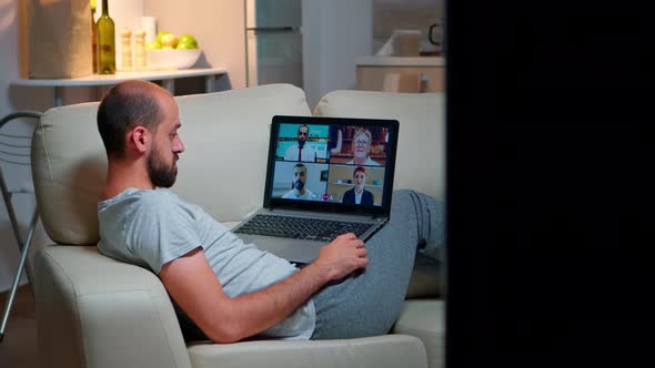 Tired Man in Pajamas Sitting on Sofa Falling Asleep While Having Online Business Videocall with