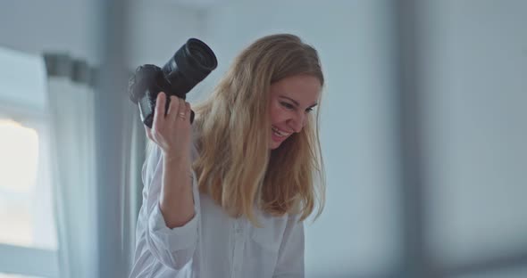 Young and Beautiful Female Photographer Taking Pictures Makes Professional Footage and Looks Into