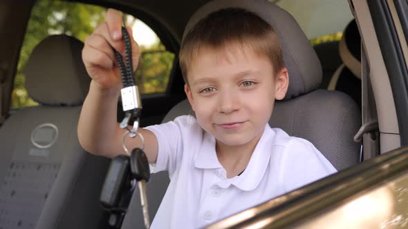 A Little Boy is Sitting in a New Car in the Front Seat with Keys in His Hands