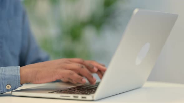 Hands of African Man Typing on Laptop Keyboard Close Up