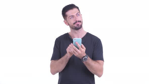 Happy Young Handsome Bearded Man Thinking While Using Phone