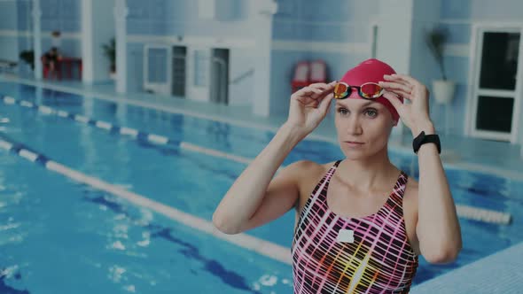 Young Professional Female Swimmer Putting on Her Goggles on Her Face