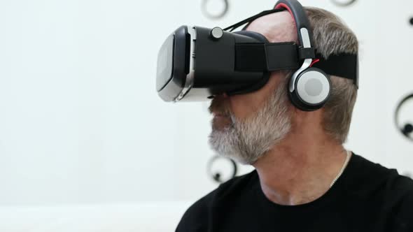 Adult Man Using Virtual Reality Glasses at Home with Wireless Headphones