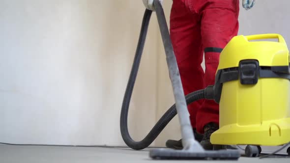 Worker is Cleaning Dust with a Vacuum Cleaner on the Floor