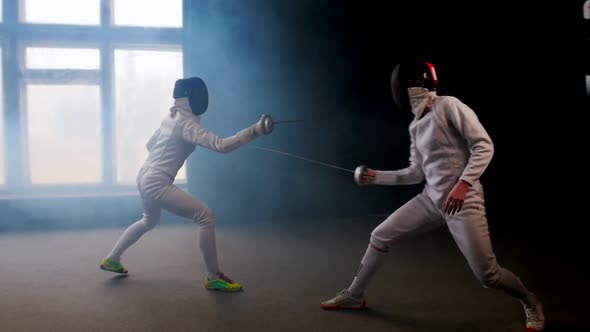 Two Young Women Fencers Having a Training Duel in the Studio