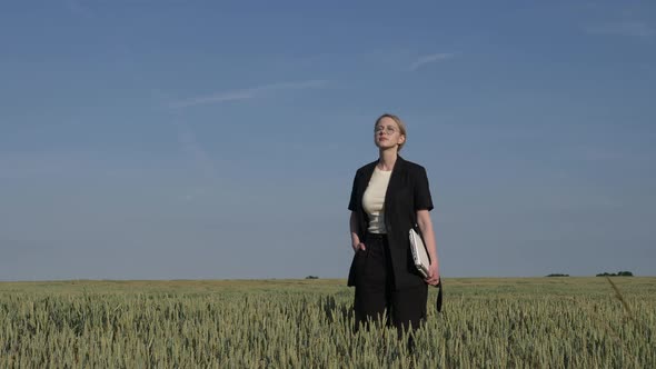 employee of an agricultural firm with a laptop checks the quality of wheat in the field