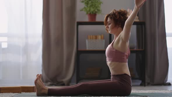 Woman is Sitting in Lotus Position on Floor in Apartment Doing Exercises for Stretching Side View on