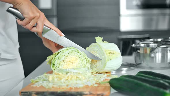 Closeup of Woman's Hands Cutting Cabbage in Kitchen