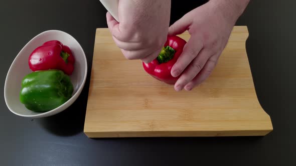 Male Hands Cutting Sweet Red And Green Bell Peppers On A Wooden Chopping Board For A Healthy Dish -