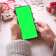 Woman holding smartphone with vertical green screen on Christmas background with gifts. - VideoHive Item for Sale
