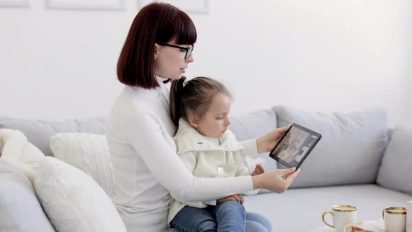 Mother and Little Daughter with Running Nose Having Video Call at Home with Her Female Confident