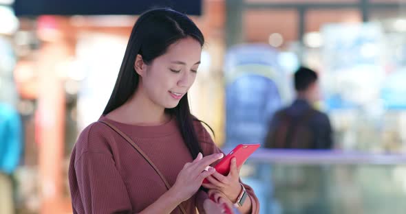 Woman checking discount pn cellphone inside shopping mall