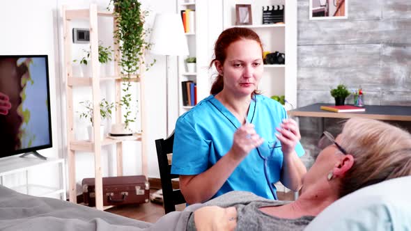 Young Female Doctor Using Stethoscope to Listen Old Woman Heartbeat