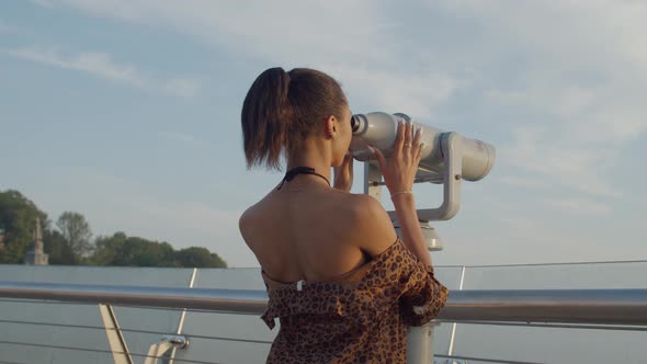 Woman Looking Through Tourist Telescope at Dawn