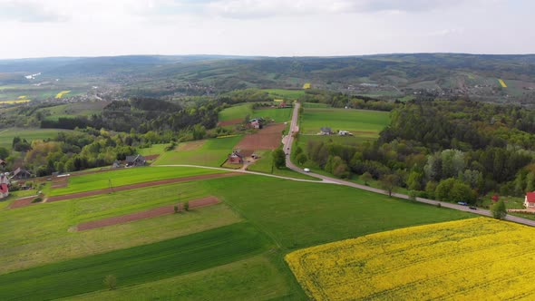 Aerial Drone View of Green Fields, Hills and Trees in a Village with Small Houses. Poland.