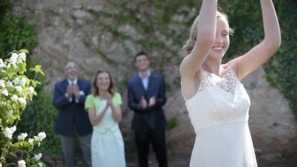 Newlywed bride throwing bouquet to wedding guest