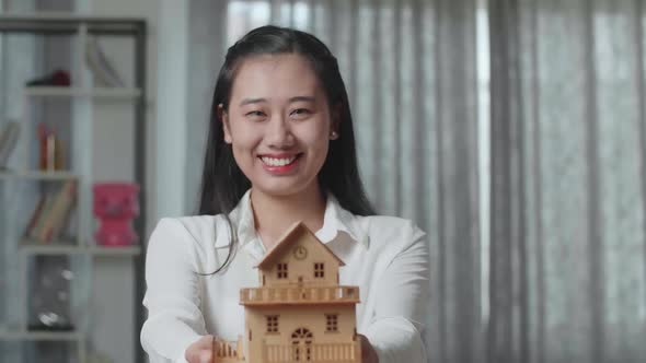 Close Up Of Asian Woman Smiling And Showing House Model To Camera In The New House