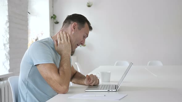 Tired Man with Neck Pain Working on Laptop