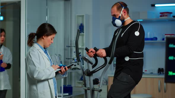 Doctor Asking Patient About His Health While Sportsman Running on Cross Trainer