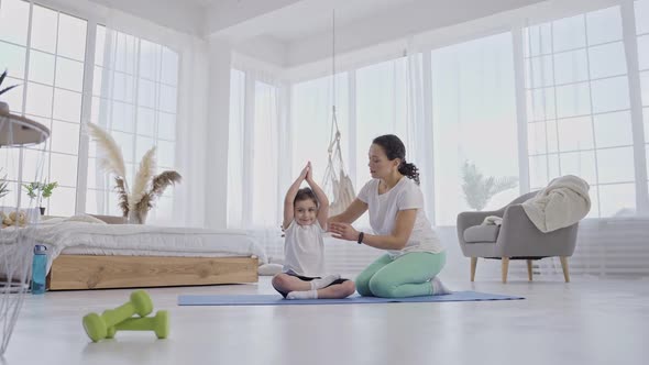 Caring Mom Helping Little Girl to Keep Yoga Pose