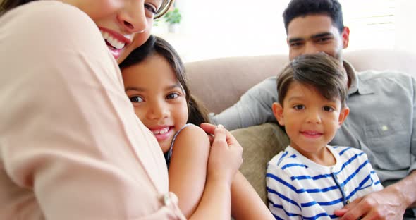Happy family sitting on sofa and embracing in living room