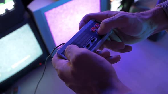 Man plays video games the console on the background of old TVs in the led room