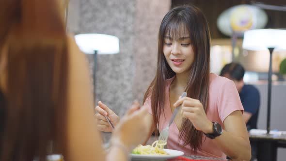 Asian young beautiful woman having lunch and laughing with friend with smile face in a restaurant.