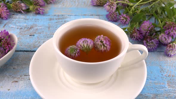 Brewing a tisanes from red clover in a white cup. 