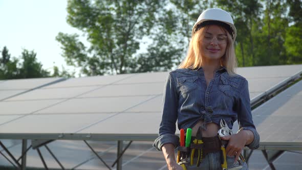 Female Engineer in a White Helmet Spirit Level is at the Solar Power Station