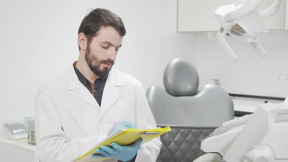 Professional Dentist Filling Medical Documents at His Office