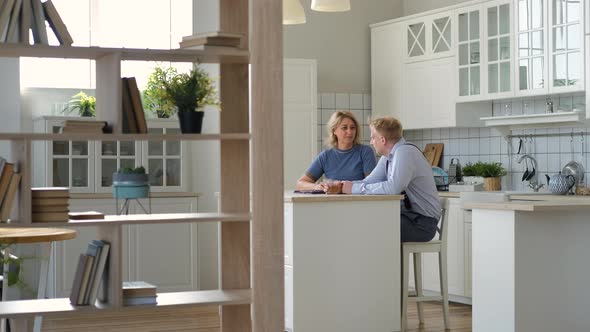 Mature Mother with Grown Son Chatting in Kitchen