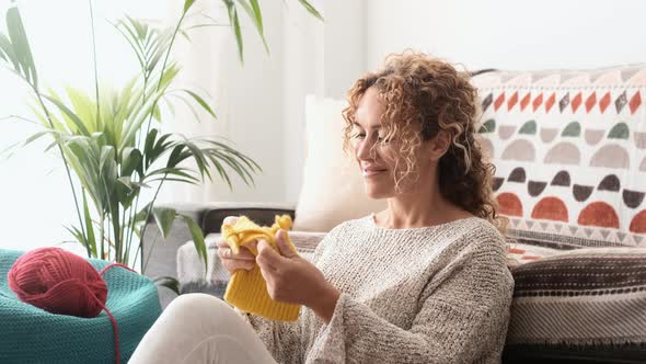 Adult attractive woman at home in knitting work activity using colorful wool.