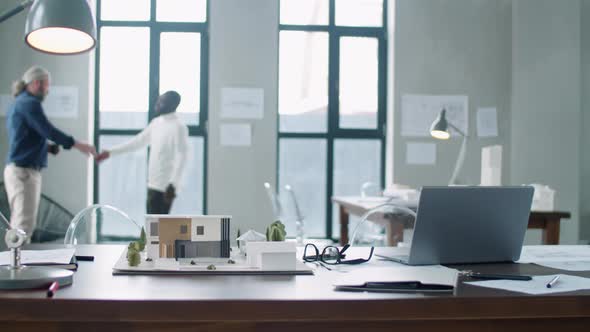 Office Desk of Architect with Building Model and Laptop