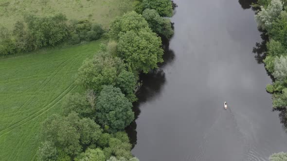 Narrow blackwater river with lone person paddleboarding, countryside