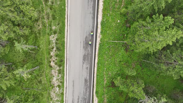 Flying above motorbikers and cyclists riding down a winding mountain road in the Dolomites