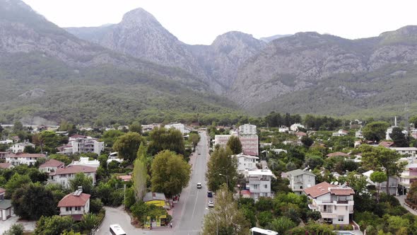 Aerial View of a Beautiful Town Among Trees at the Foot of the Mountains and Busy Traffic on the