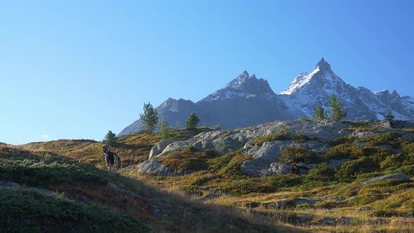 One person with backpack hiking in high altitude mountain environment, dramatic alpine landscape