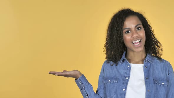 African Girl Showing Product at Side Yellow Background
