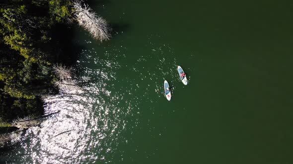 People Ride on SUP Board in the Mountain Lake