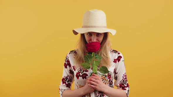 Studio Shot of a Pretty Young Cheerful Woman with Blonde Hair in a Fair Hat and a Floral Blouse