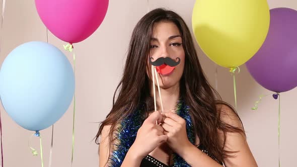 Close up of brunette woman playing with props in party photo booth