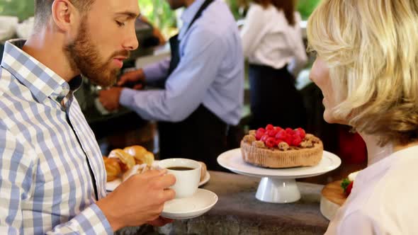 Male owner serving coffee to customers