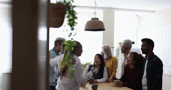 Multiracial happy friends having fun drinking coffee at home kitchen