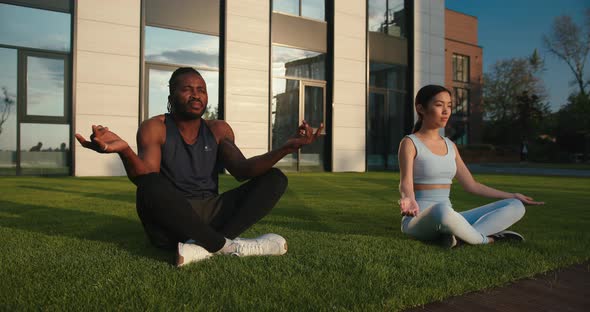 AfricanAmerican Guy with Asian Lady Meditates on Lawn